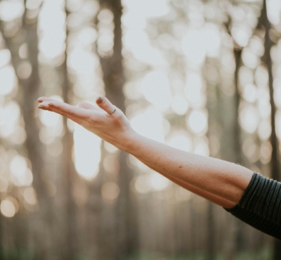 Frau streckt Arme aus im Wald